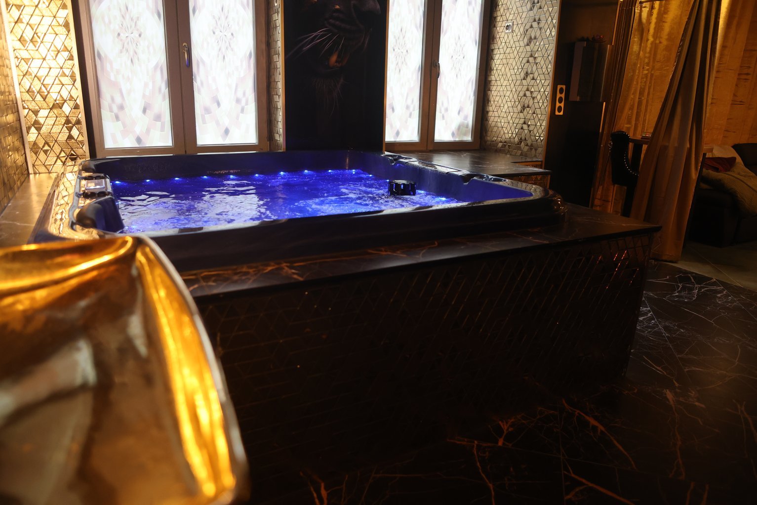 Jacuzzi éclairé de bleu dans son écrin de marbre et de dorures